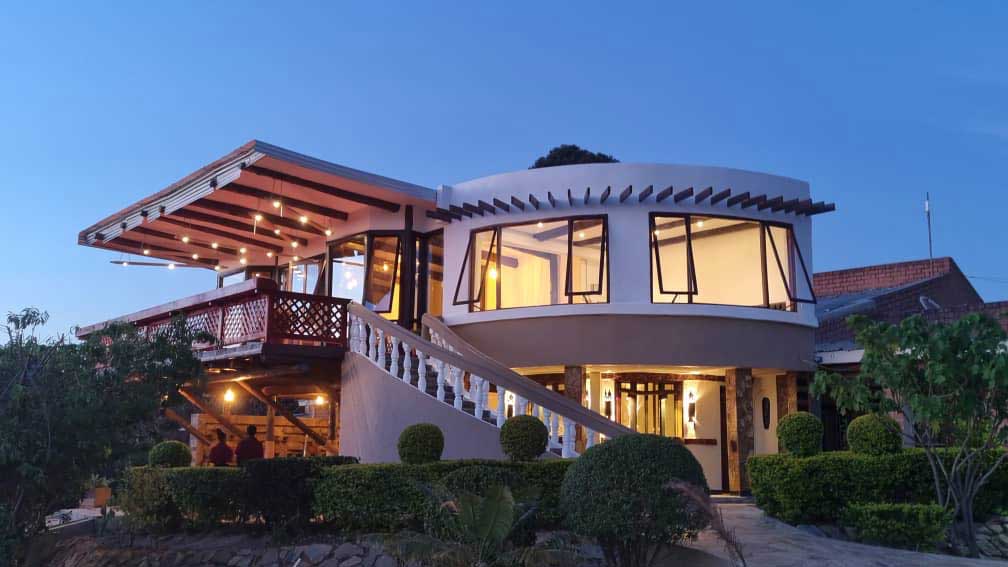 Saivilla Hotel's curved building lit up at dusk